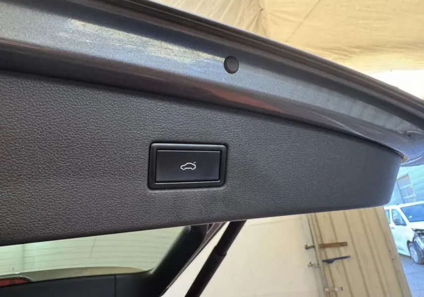 Gros plan sur le bouton d'ouverture électrique du coffre, situé sur le hayon intérieur gris foncé du Volkswagen Tiguan Allspace.