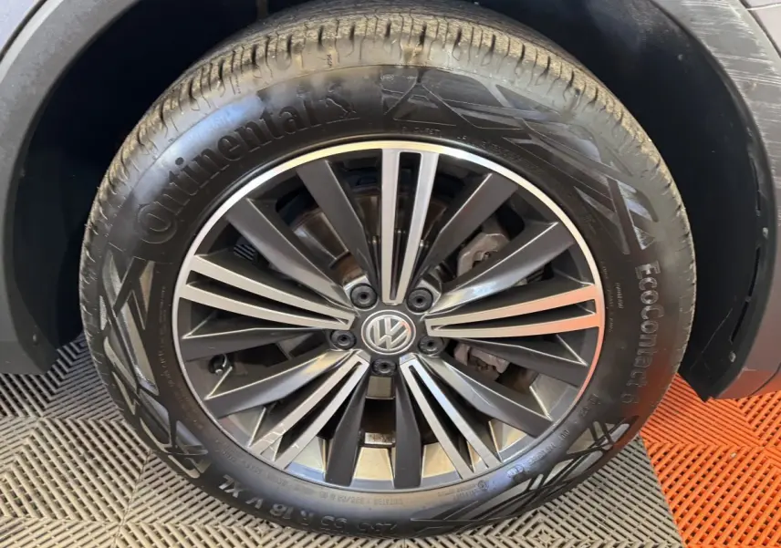 Gros plan sur la roue avant droite avec jante alliage noir et gris du Volkswagen Tiguan Allspace gris foncé.