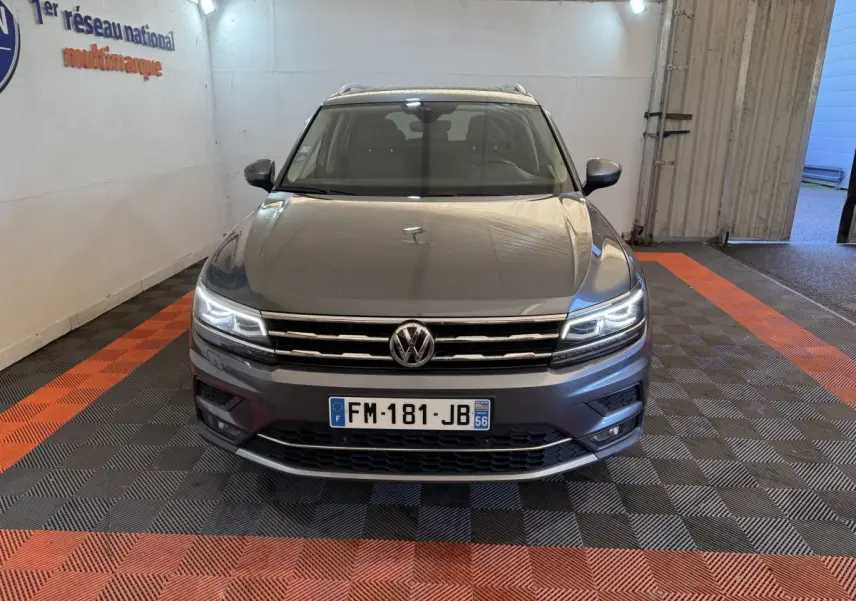 Vue de face du Volkswagen Tiguan Allspace gris foncé avec phares LED allumés dans un garage.