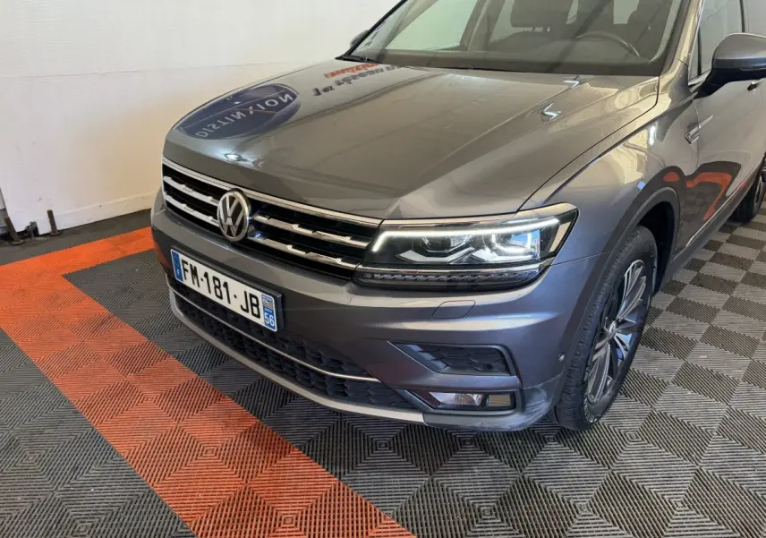 Vue 3/4 avant droit d'un Volkswagen Tiguan Allspace gris foncé avec phares LED et calandre chromée.
