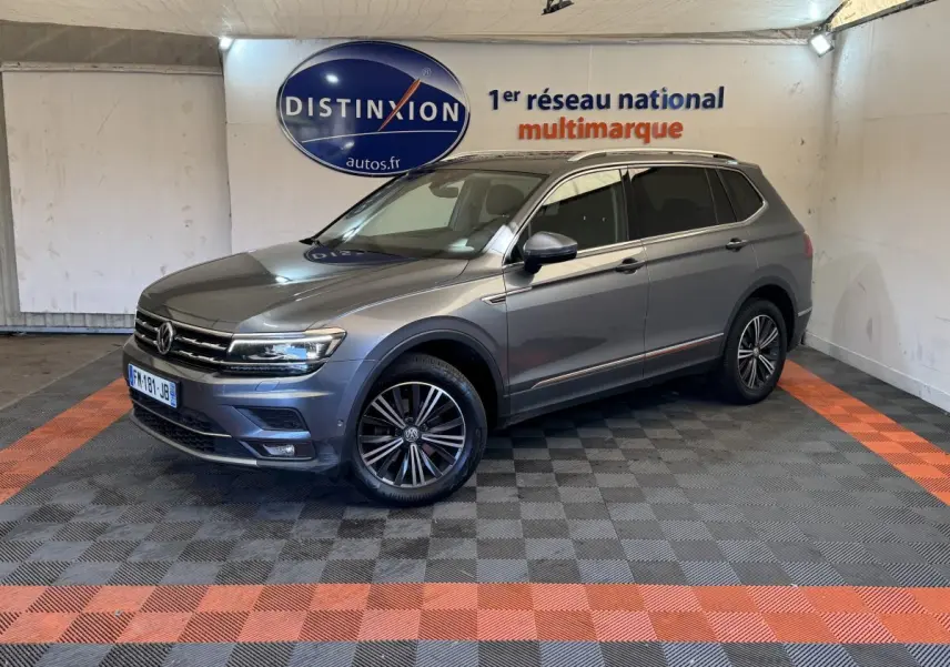 Volkswagen Tiguan Allspace gris foncé en 3/4 avant droit, avec jantes alliage et barres de toit chromées.