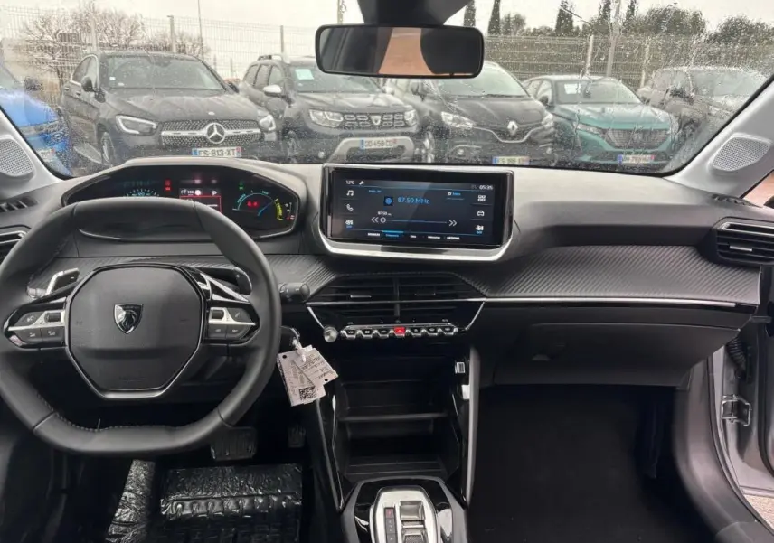 Vue intérieure avant du Peugeot 208 Hybrid gris, avec volant multifonction, écran tactile et tableau de bord numérique.