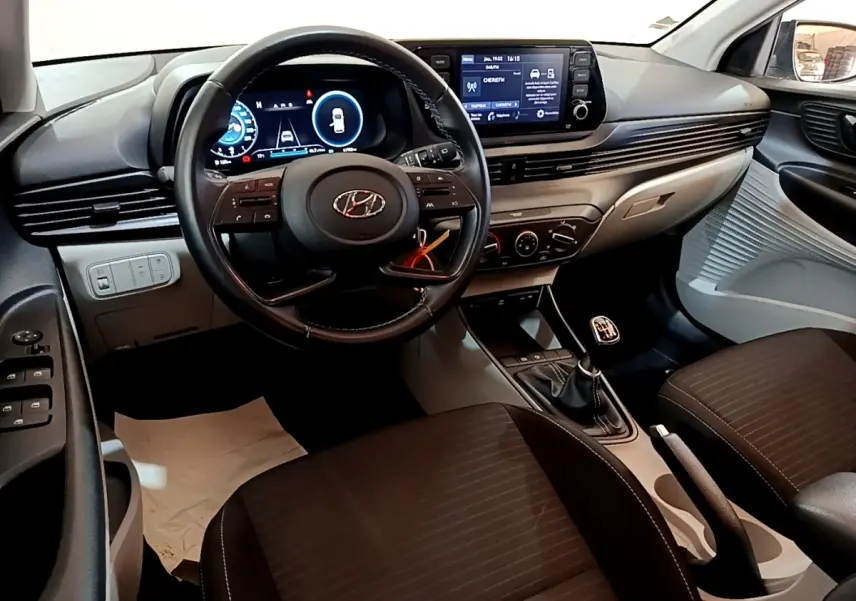 Intérieur Hyundai i20 2022 vu de face, volant cuir multifonctions, écran tactile et boîte manuelle noire.