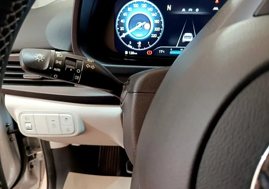 Vue intérieure centrée sur le tableau de bord et volant cuir de la Hyundai i20 gris clair, affichage numérique et commandes éclairage.