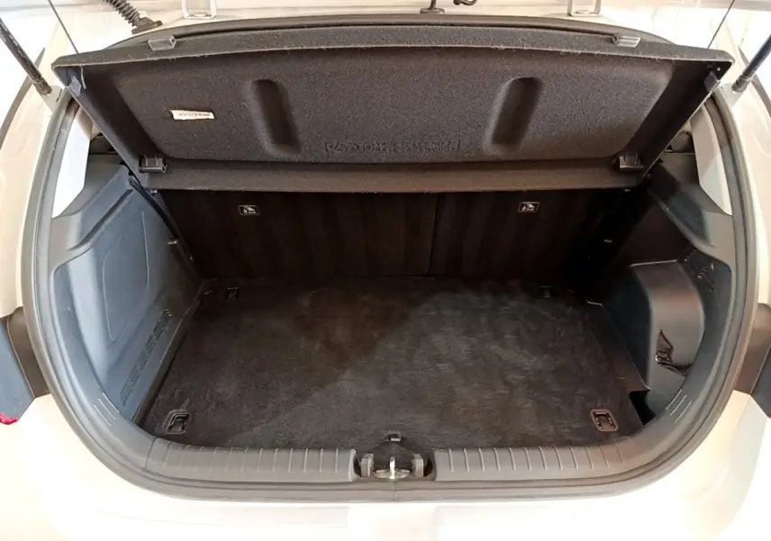 Coffre ouvert vu de l'arrière d'une Hyundai i20 gris clair, montrant l'espace de chargement vide et la tablette amovible.