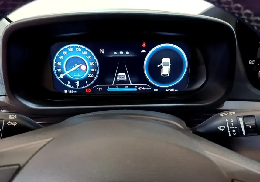 Vue rapprochée du tableau de bord numérique de la Hyundai i20 hybride 2022, affichage vitesse et alertes sur fond noir.