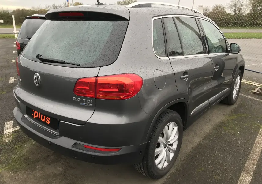 Vue 3/4 arrière droite d'un Volkswagen Tiguan Sportline gris foncé avec logo 2.0 TDI et jantes alliage.