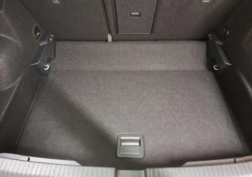 Coffre vide du Volkswagen T-ROC 1.5 TSI 150 DSG7 R-LINE 2024, vue plongeante sur le tapis gris foncé.