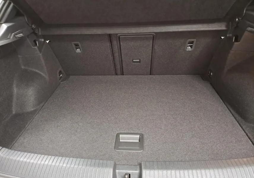Coffre spacieux et propre du Volkswagen T-Roc 2024, vue intérieure arrière, avec revêtement gris foncé uniforme.