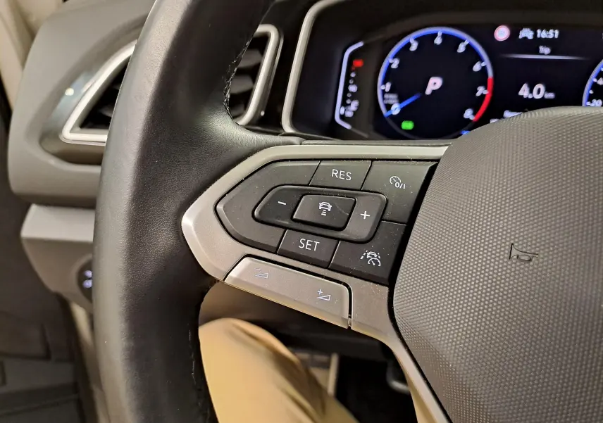 Gros plan sur le volant à gauche du Volkswagen T-Roc 2024, avec commandes de régulateur et tableau de bord numérique.