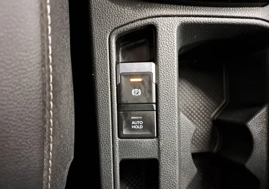 Gros plan sur les commandes de frein de stationnement électronique et Auto Hold dans un Volkswagen T-Roc Gris Ascot 2024.