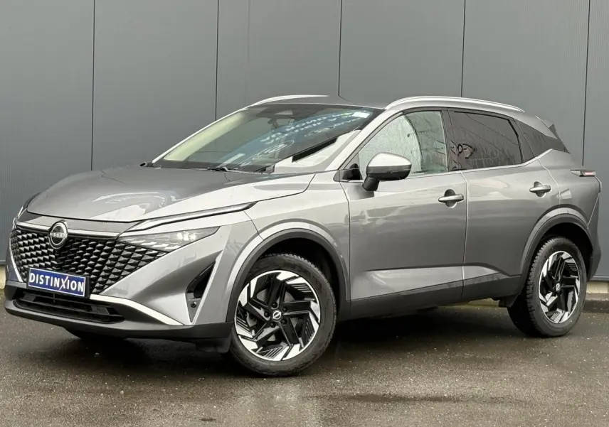 Nissan Qashqai gris Squale en 3/4 avant droit, avec calandre noire texturée et jantes alliage bicolores.