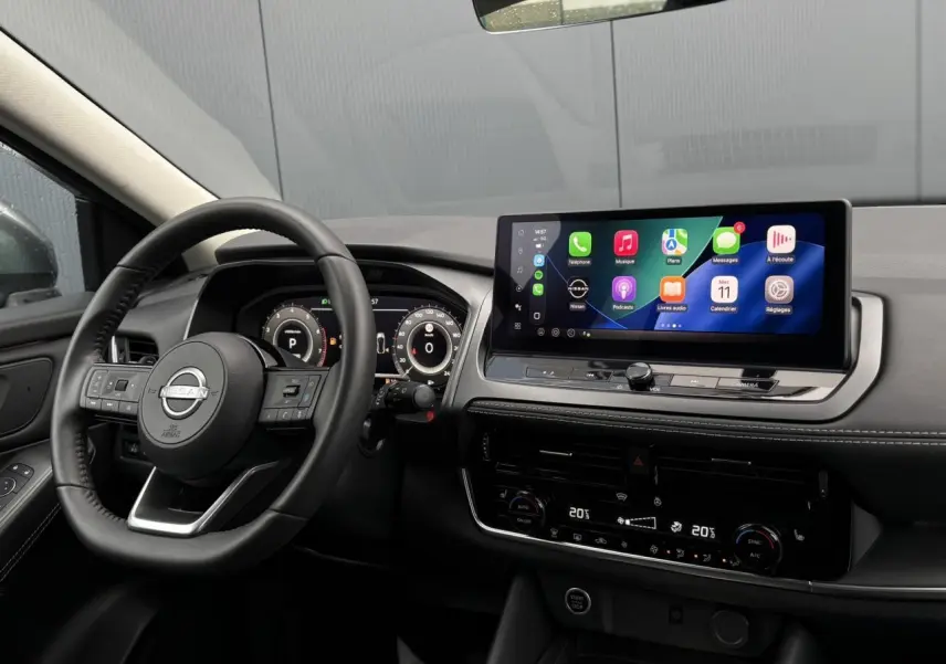 Vue intérieure côté conducteur du Nissan Qashqai 2024, tableau de bord noir avec écran tactile et affichage numérique.