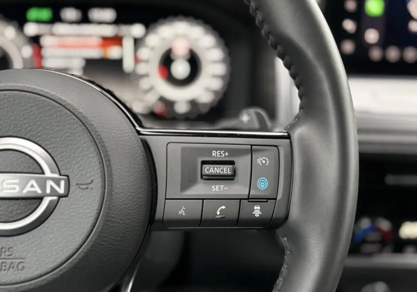 Gros plan sur le volant cuir noir du Nissan Qashqai 2024, avec commandes de régulateur de vitesse et assistance au pilotage.