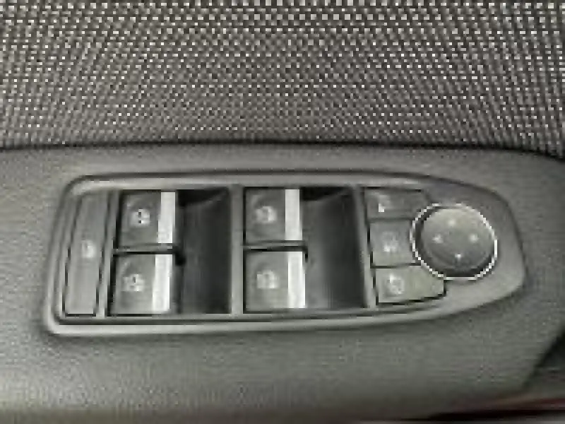 Gros plan sur les commandes électriques des vitres et rétroviseurs sur la porte côté conducteur du Renault Captur rouge 2025.