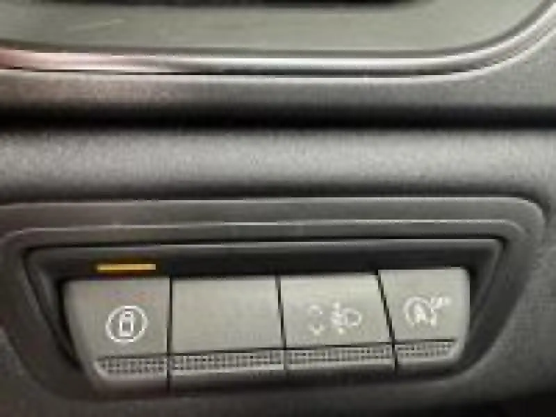 Gros plan sur les boutons de commande du tableau de bord du Renault Captur rouge 2025, avec indicateur lumineux orange.