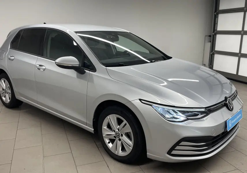 Volkswagen Golf 2022 couleur reflet d'argent vue 3/4 avant droit dans un garage avec phares allumés.