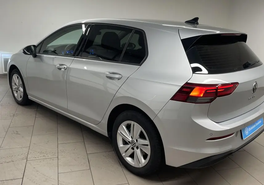 Volkswagen Golf 2.0 TDI 2022 en reflet d'argent, vue 3/4 arrière côté gauche avec feux arrière allumés.