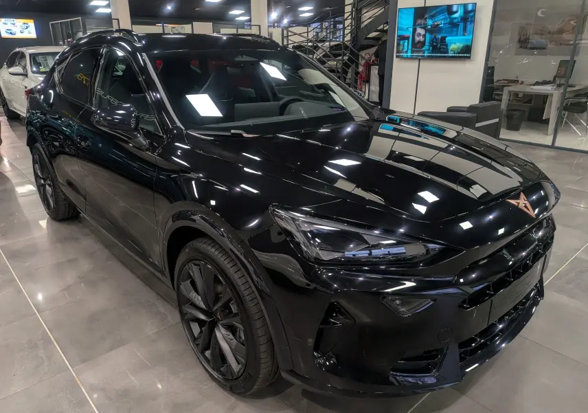 Vue 3/4 avant droite d'un CUPRA Formentor eHybrid noir minuit, avec jantes noires et intérieur sombre visible.