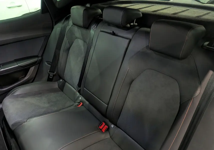 Vue intérieure de la banquette arrière en cuir noir et alcantara avec surpiqûres orange du CUPRA Formentor eHybrid 2025.