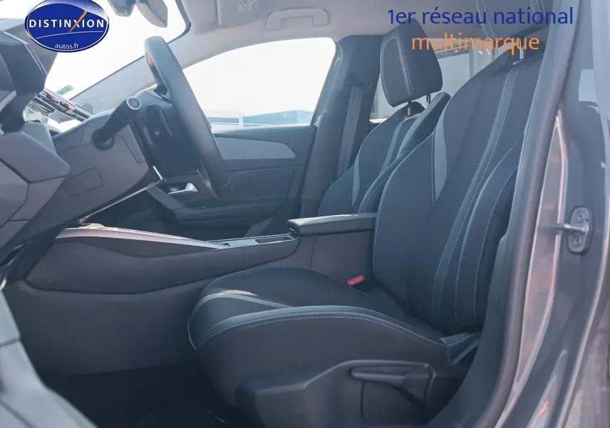 Vue intérieure côté conducteur de la Peugeot 408 Hybrid 145 allure gris sélénite, mettant en valeur les sièges et l'accoudoir central.