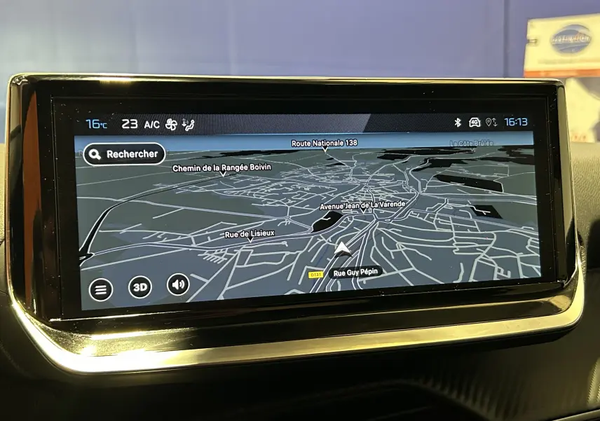 Écran tactile du GPS intégré d'une Peugeot 208 2025, affichant une carte en 3D avec navigation active.