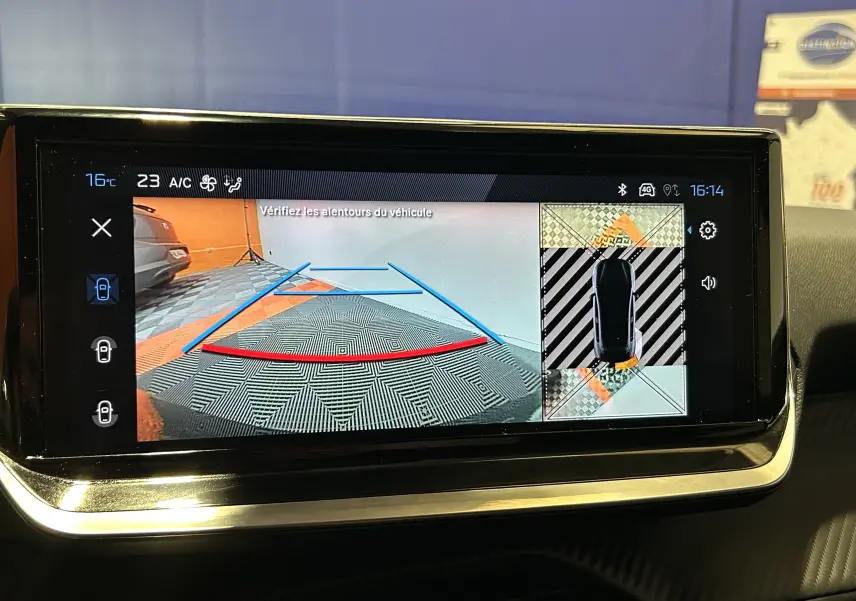 Écran central de la Peugeot 208 gris Selenium montrant la caméra 360° avec vue arrière et top-down du véhicule.