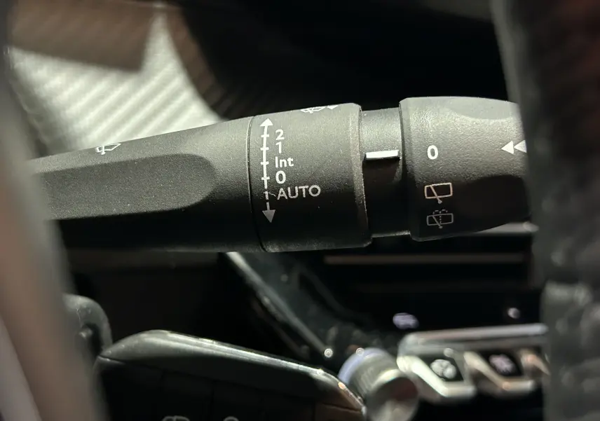 Gros plan sur la commande d’essuie-glace à gauche du volant dans l’habitacle d’une Peugeot 208 gris Selenium.