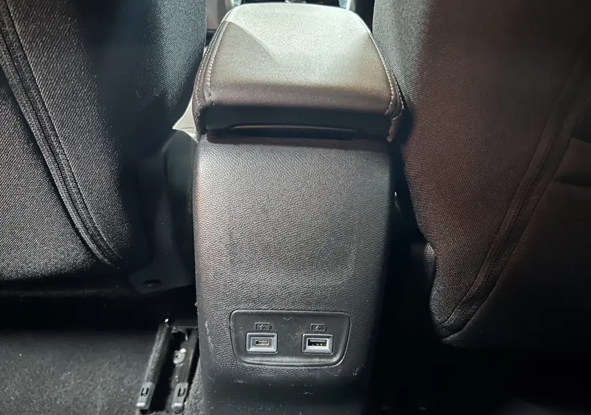 Vue rapprochée de la console centrale arrière de la Peugeot 208 gris Selenium, avec ports USB visibles entre les sièges noirs.