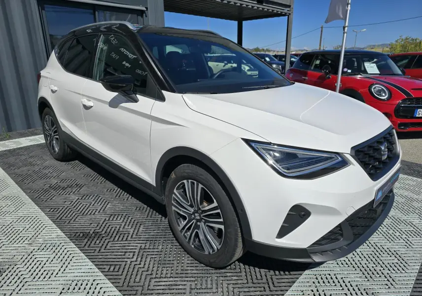 SEAT Arona blanc toit noir en 3/4 avant droit, avec calandre FR et jantes alliage 17 pouces visibles.