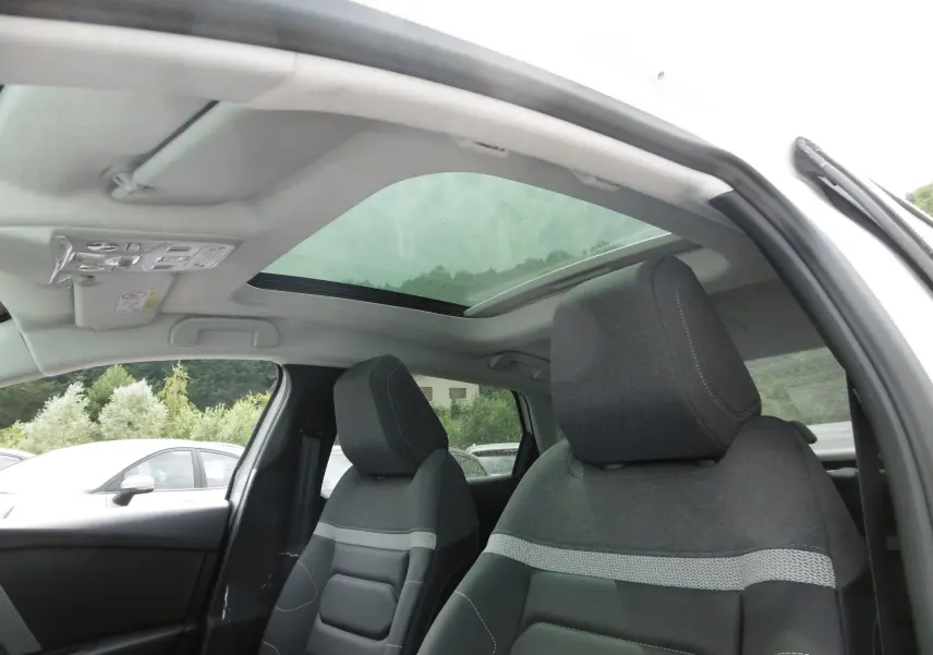 Vue intérieure du toit panoramique et des sièges avant gris foncé de la Citroën C4 X blanc polaire 2023.