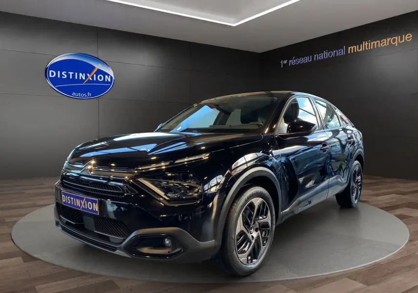 Vue 3/4 avant droite d'une Citroën C4 BlueHDi 130 Plus noire Perla Nera avec jantes alliage et calandre distinctive.