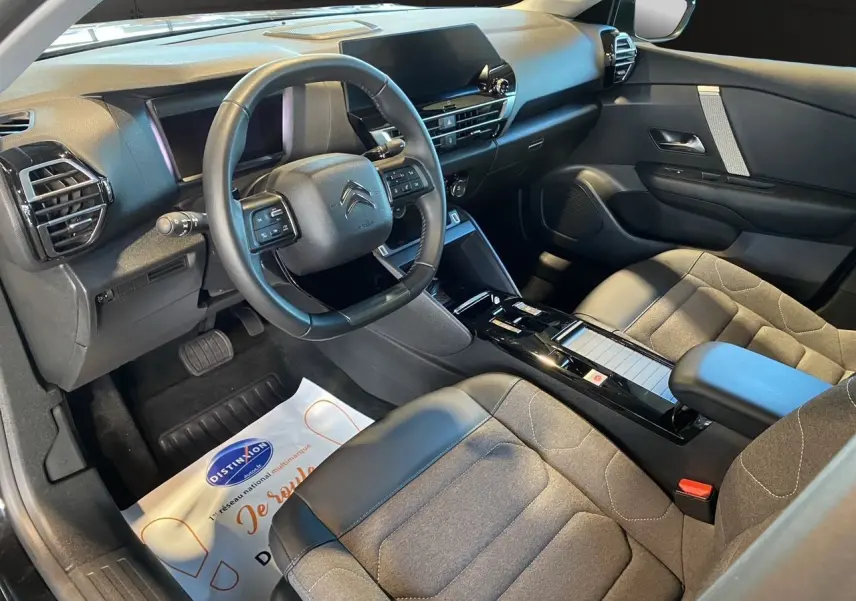 Intérieur avant droit du Citroën C4 2023 noir Perla Nera, avec tableau de bord moderne et sièges gris noir.