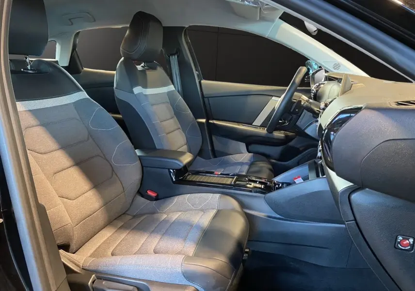Vue intérieure côté conducteur de la Citroën C4 2023 noir Perla Nera avec sièges bi-matière gris et noir.