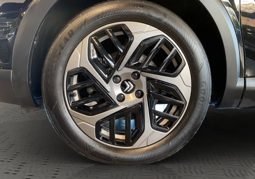 Gros plan sur la roue arrière droite d'une Citroën C4 noire Perla Nera, soulignant le pneu Goodyear et l'arche de roue.