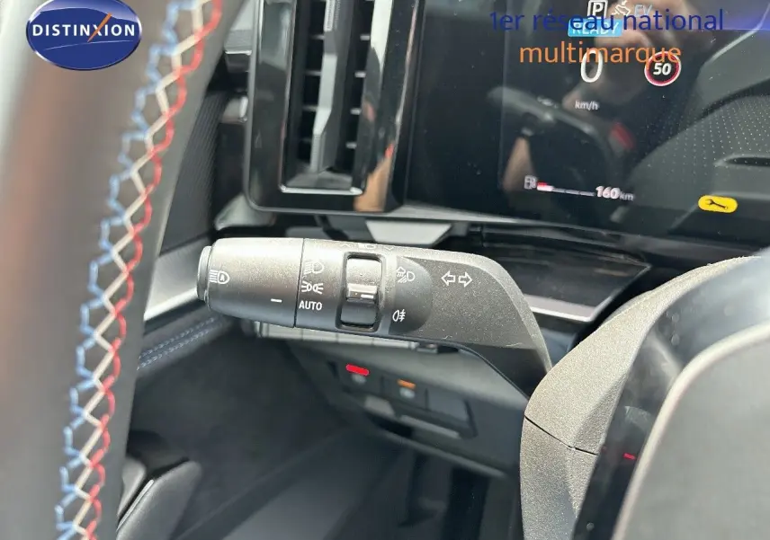 Gros plan sur la manette de clignotants du tableau de bord d'un Renault Austral 2024 bleu iron avec volant surpiqué.