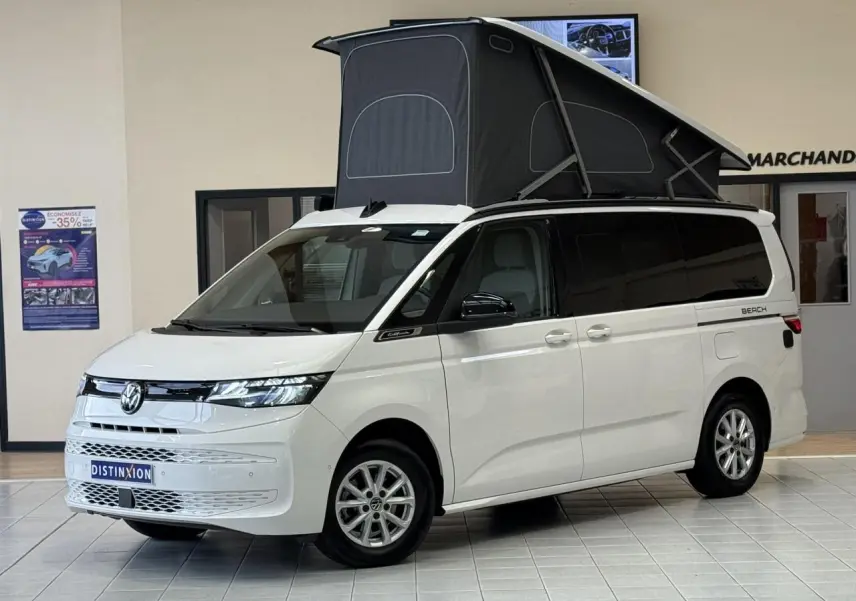 Volkswagen California T7 blanc Candy en 3/4 avant avec toit relevable noir déployé en intérieur showroom.