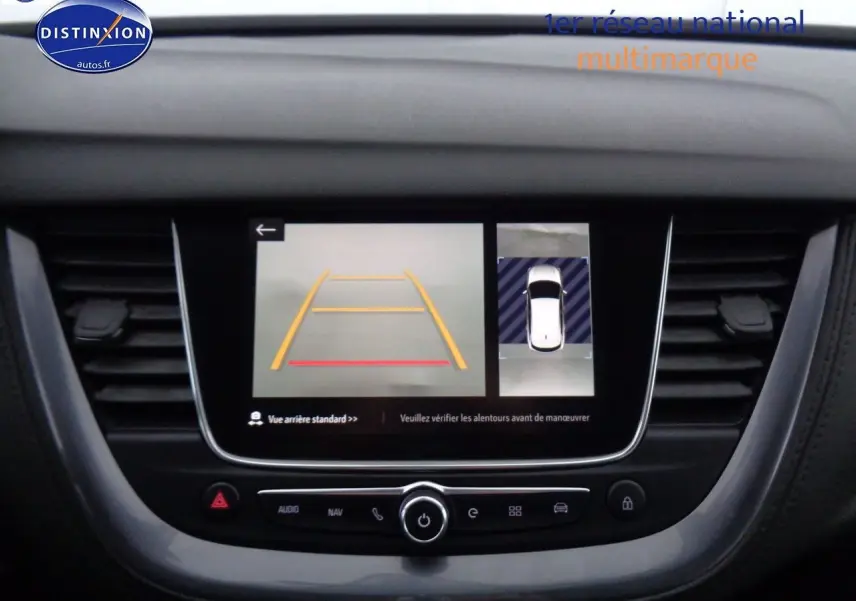 Écran central de l’Opel Grandland X blanc nacré montrant la caméra de recul et l’aide au stationnement en vue intérieure.