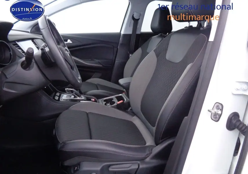 Vue intérieure côté conducteur de l'Opel Grandland X blanc nacré, sièges tissu et cuir noir avec console centrale visible.