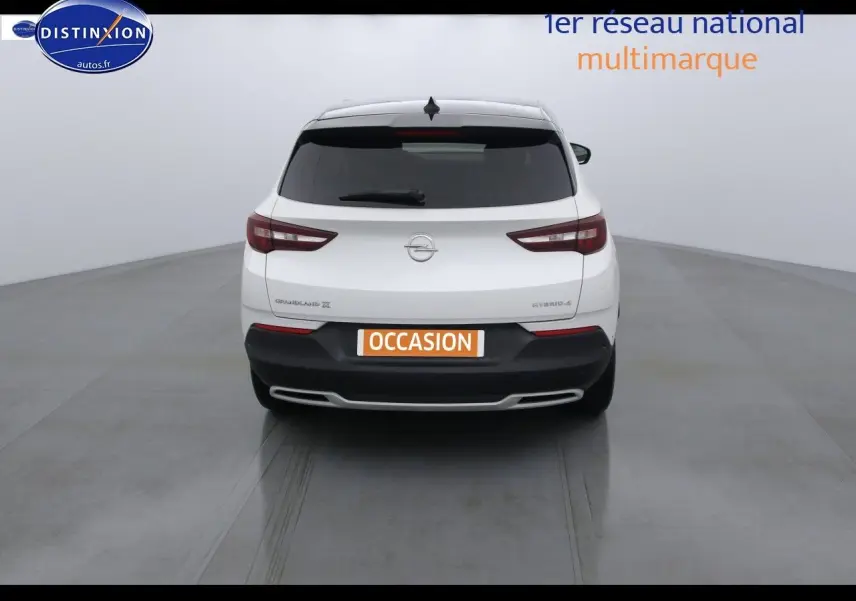 Vue arrière d'un Opel Grandland X hybride blanc nacré, avec hayon fermé et feux arrière allongés distinctifs.