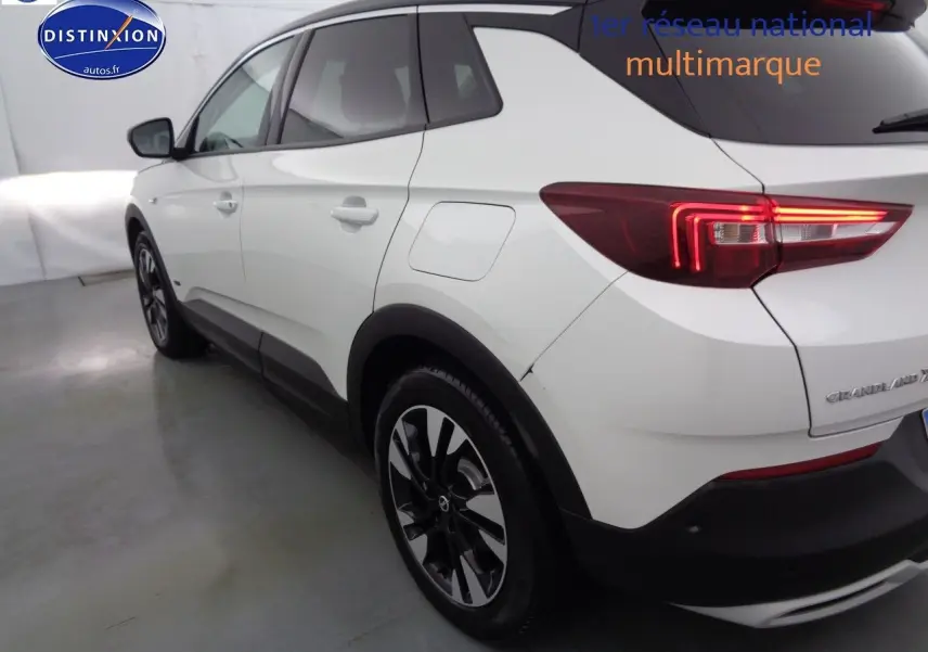 Vue 3/4 arrière côté gauche d'un Opel Grandland X blanc nacré avec feux arrière LED et jantes noires.
