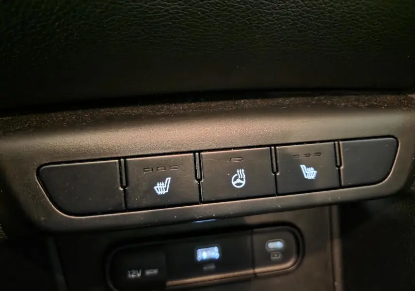 Gros plan sur les commandes de sièges chauffants et volant chauffant du Kia Sportage noir 2022.