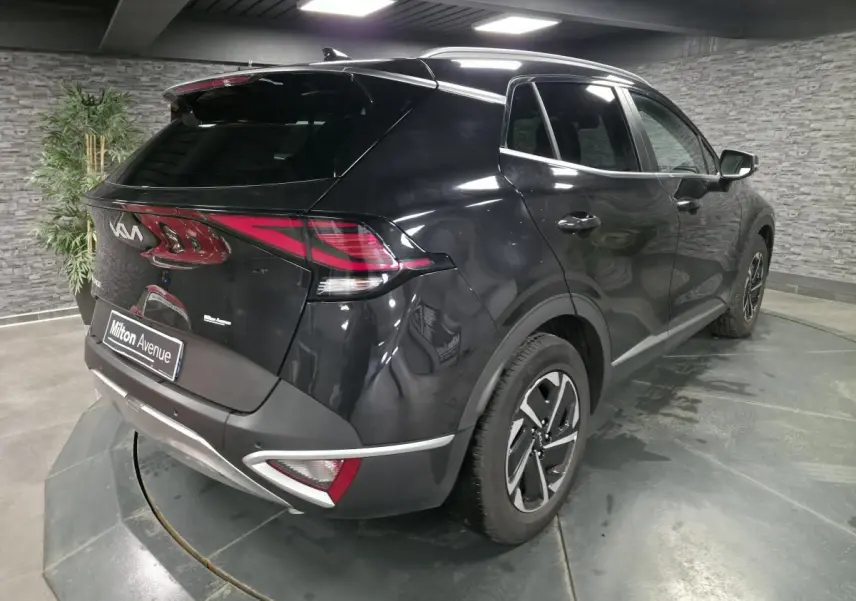 KIA SPORTAGE noir en 3/4 arrière droit, avec feux arrière LED et jantes alliage 17 pouces dans un showroom.