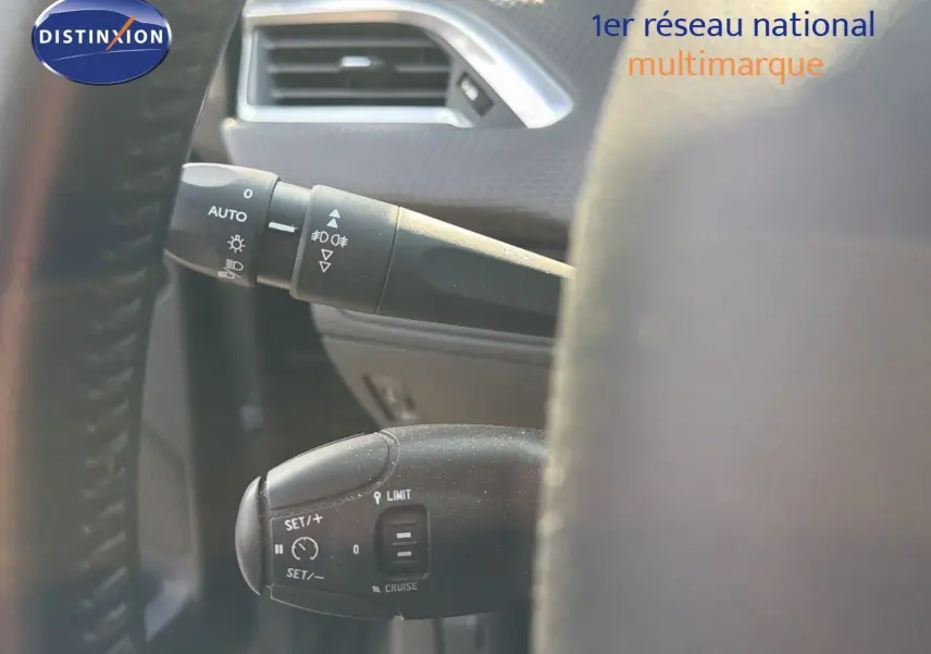 Gros plan sur les commandes au volant du Peugeot 2008 gris platinium, mettant en valeur les fonctions de régulateur et éclairage.
