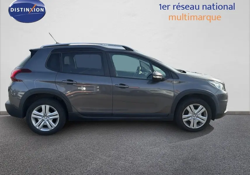 Peugeot 2008 gris platinium vue de profil côté gauche, SUV compact avec jantes alliage et barres de toit.