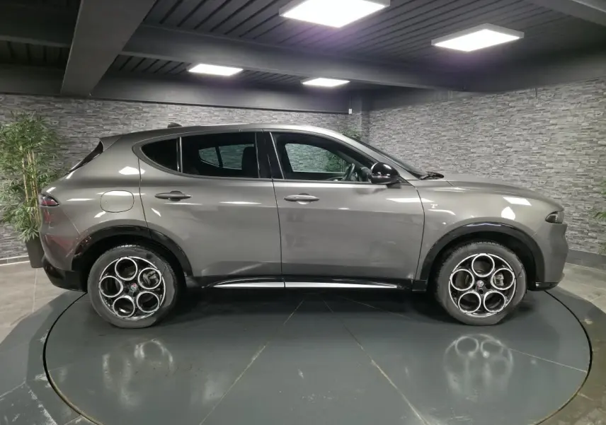 Vue de profil côté gauche d'un Alfa Romeo Tonale gris métallisé 2023 avec jantes alliage 18 pouces et rétroviseurs noirs brillants.