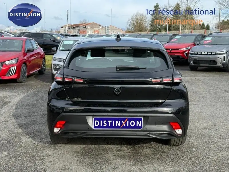 Vue arrière d'une Peugeot 308 noire Perla Nera 2024, avec feux arrière distinctifs et logo central sur un parking.