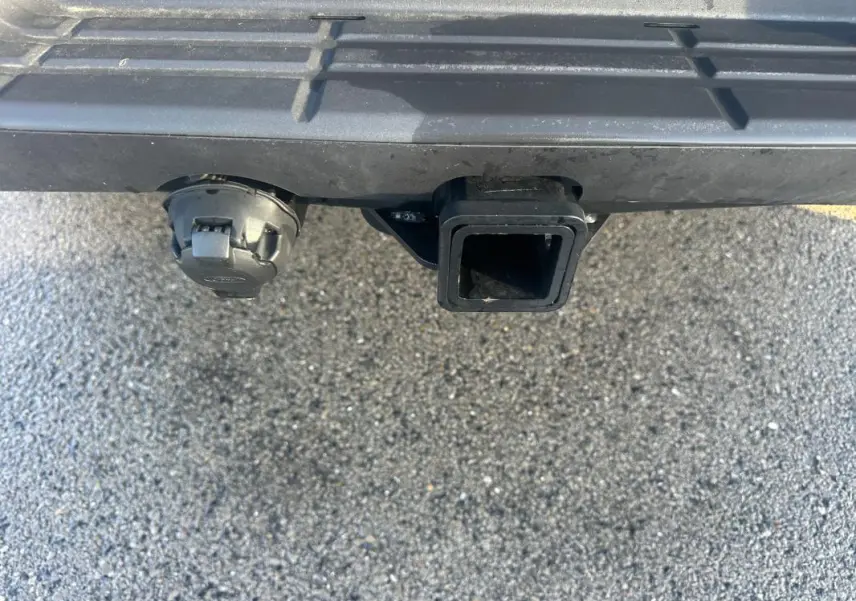 Gros plan sur l'attelage et la prise électrique sous le pare-chocs arrière noir du Ford Ranger blanc.