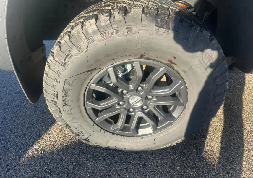 Gros plan sur la roue avant gauche du Ford Ranger Raptor 2025, jante alliage noire et pneu tout-terrain.