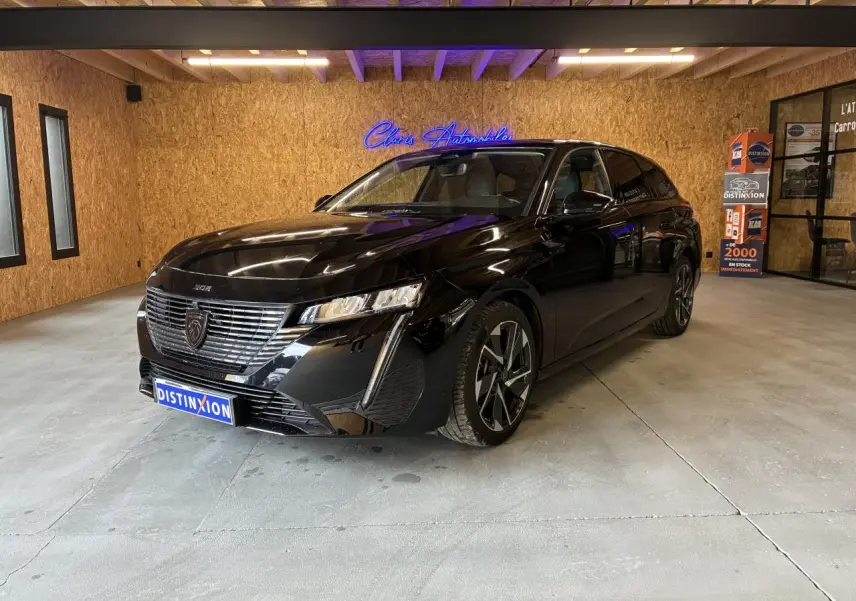 Peugeot 308 SW noire vue en 3/4 avant droit dans un showroom avec éclairage intérieur.